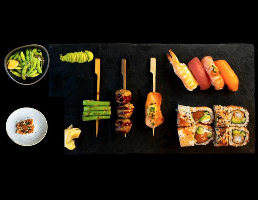 Sticks, nigiri og maki anrettet på sort skiferplade med edamame